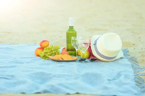Picnic background with bag, grape and white wine on the beach by blue sea Stock Photos