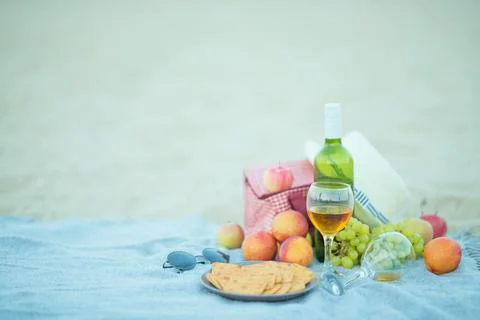 Picnic background with bag, grape and white wine on the beach by blue sea Stock Photos