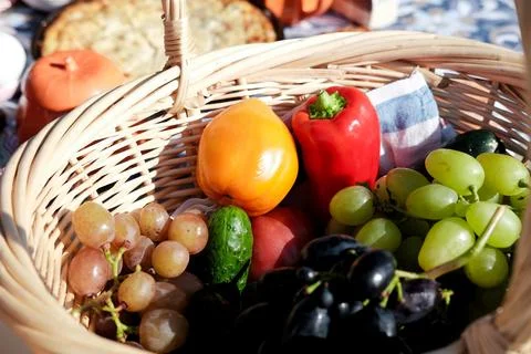 Picnic basket with different types of grapes, red pepper, tomatoes and cucu.. Stock Photos