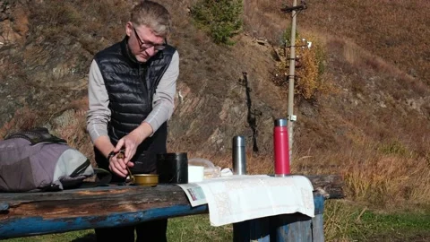Picnic in nature. Standing at the table, man pours hot noodle soup into cup. 4K Stock Footage 167580828