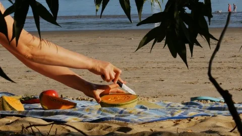 Picnic on a river beach - cutting melon - 4k Stock Footage 82295377