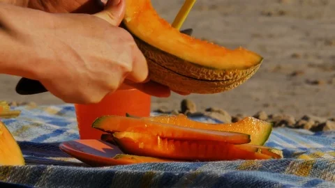 Picnic on a river beach - cutting melon - 4k Stock Footage 82299622