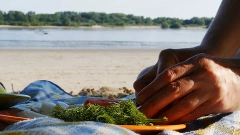Picnic on a river beach - cutting tomato for salad - 4k Video stock 82307606