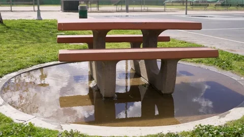 Picnic table in the park with the reflection in the puddle of water, slow motion Stock Footage 234237333