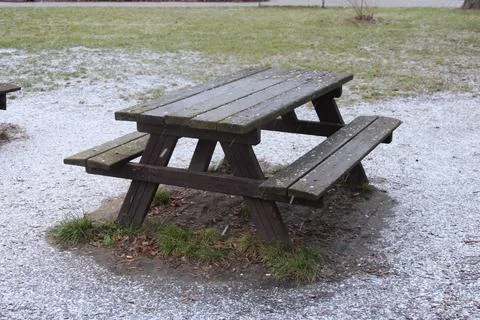 Picnic table surrounded by light snow in a park setting during winter Stock Photos
