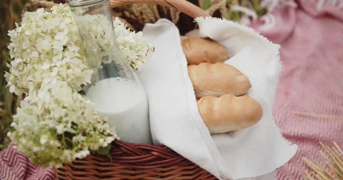 Picnic wicker basket with bread, milk and wildflowers Stock Footage 142245920