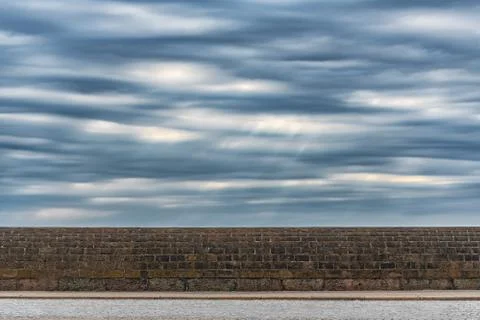 Picture of dramatic stormy sky with clouds over the stone wall Stock Photos