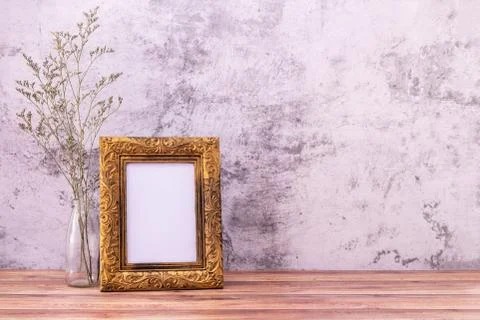 Picture frame with flowers on wall background and wooden table. Poster produc Stock Photos