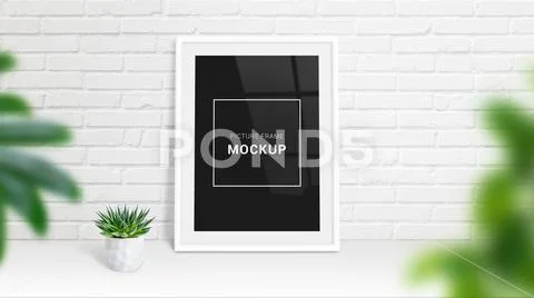 Picture frame mockup leaned on white brick wall. Plant beside PSD-Vorlage