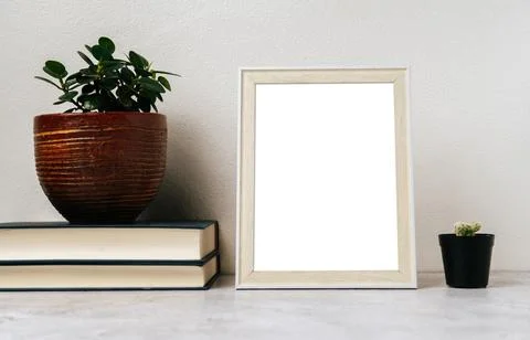 A picture frame placed on a book with a small plant pot Stock Photos