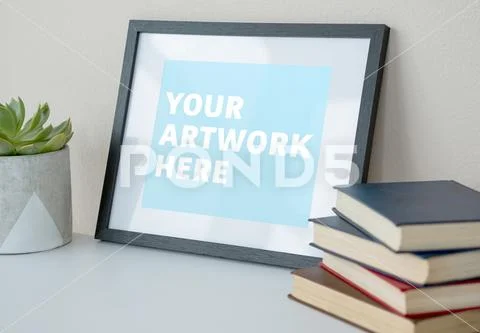 Picture frame with stack of books and pot plant on table PSD Template