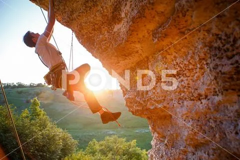 Picture of man clambering over rock. Stock Photos