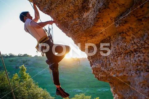 Picture of man clambering over rock. Stock Photos