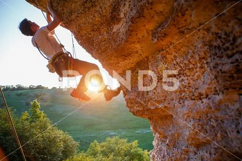 Picture of man clambering over rock. Stock Photos