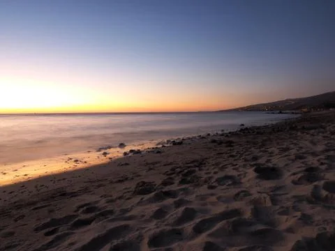 Picture of the ocean at dusk while the lights turning on in the city Stock Photos