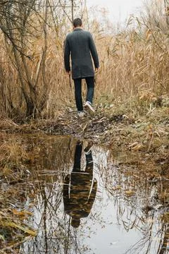 Picture of a reflection of a man on the water with yellow autumn leaves Stock Photos