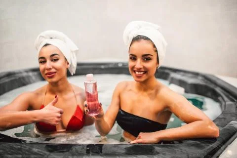 Picture of two models sitting in jacuzzi full of water with foam. European odel Foto stock