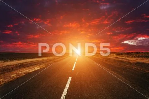 Picturesque fiery sunset over the cracked desert road Stock Photos