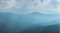 Picturesque mountain hill on background of cloud stream with foggy sunlight beam 4k or 4k+ Resolution