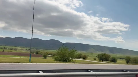 Picturesque nature view while driving through green fields and mountains Stock Footage 276694610