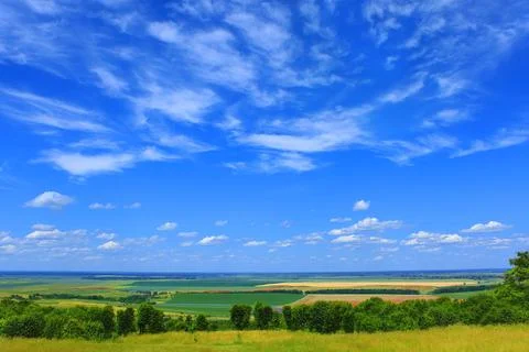 Picturesque summer cloudscape over fields, meadows, forests, roads, villages Stock Photos