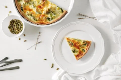 Pie with broccoli, pumpkin bite, seeds and crackers lie on a white table. Nearby Stock Photos
