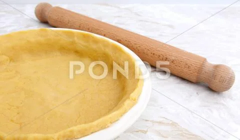 Pie dish lined with pastry with a rolling pin Stock Photos
