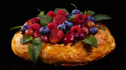 Pie with mixed berries and mint leaves rotating on black background. 4K. 库存影片 78703117
