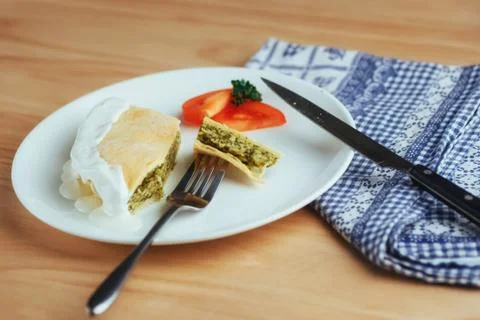Pie with spinach and tomato slice on wooden table. Stock Photos