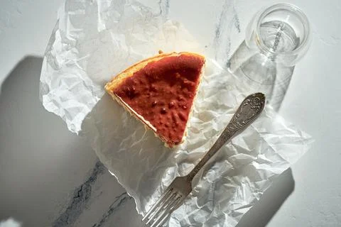 A piece of Basque cheesecake on parchment with a fork. Sunlight in the morn.. Stock Photos