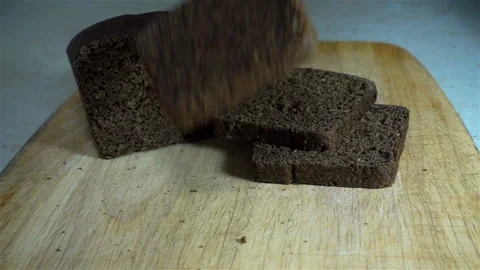 A piece of black bread falls in slow motion next to a cut loaf. Stock Footage 130520581
