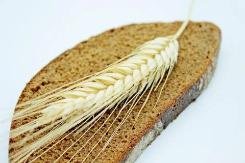 A piece of bread and rye spike located on a white background Stock Photos