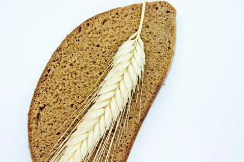 A piece of bread and rye spike located on a white background Stock Photos