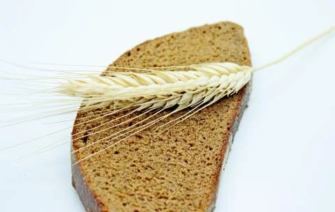 A piece of bread and rye spike located on a white background Stock Photos
