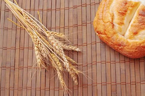 Piece of bread and spikelets of wheat on wooden background Stock Photos