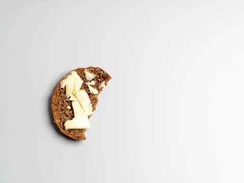 A piece of bread with butter on a light background. Savings concept. hunger Stock Photos