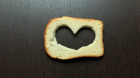 In a piece of bread carved heart on a dark background Stockbeeldmateriaal 103764638