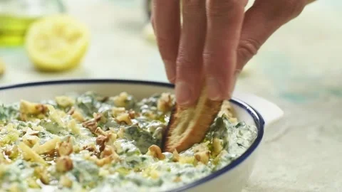 Piece of bread is dipped in spinach and yogurt dip with walnuts. Stock Footage 194922461