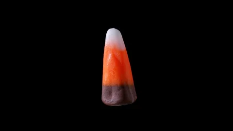 A piece of brown candy corn is seen floating and slowly rotating within a Stock Footage 116399665