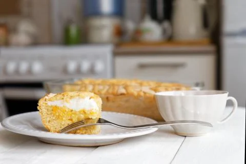 Piece of cake with lemon-orange filling and meringue on domestic kitchen. 스톡 사진