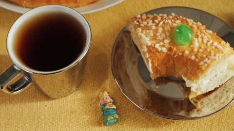 Piece of cake Roscon de reyes with plastic king figurine and cup of tea. A Stock Footage 318747329