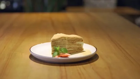 A piece of cake on the table, strawberries on a plate, honey cake, sweet Vidéo 256143217