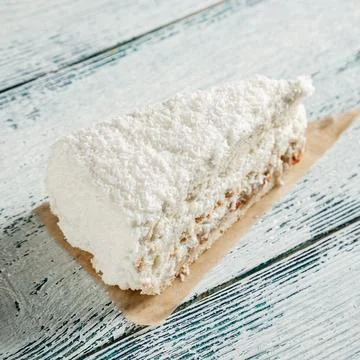 A piece of cake with white coconut chips on a wooden background made of old.. Stock Photos