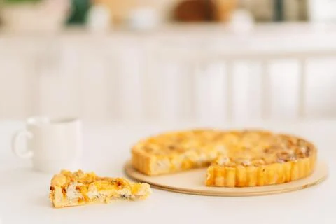 Piece of cake on white plate with fork next to cup of tea on white background Stock Photos