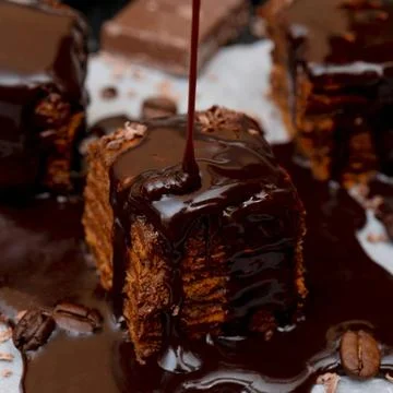 A piece of chocolate cake. Liquid chocolate flows on top of the cake. Clos... Stock Photos