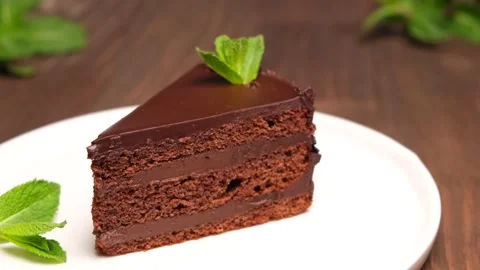 A piece of chocolate cake on a white plate decorated with mint Stock Footage 154631767