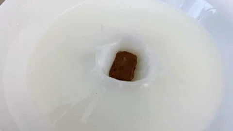 Piece of chocolate fall down in plate with milk, closeup, super slow motion Stock Footage 132780470