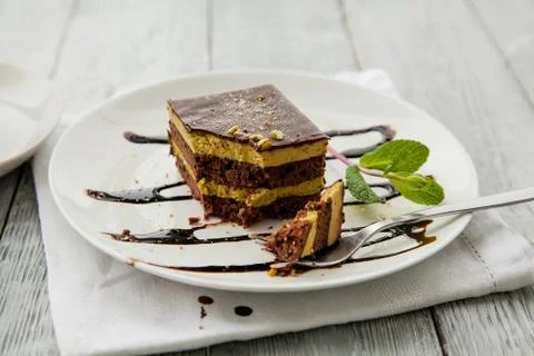 Piece of chocolate three-layer cake and miny on a white plate in a cafe Stock Photos