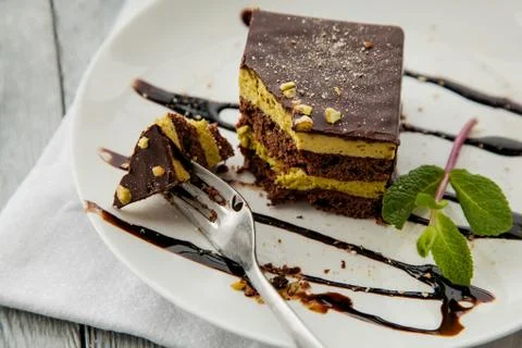 Piece of chocolate three-layer cake and miny on a white plate in a cafe Stock Photos