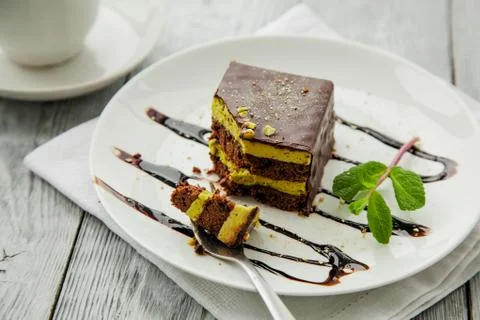 Piece of chocolate three-layer cake and miny on a white plate in a cafe Stock Photos